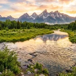 Crystal clear river winding through lush green valley with majestic mountains at sunrise (AI Generated Image)